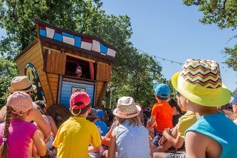 Enfants regardant un spectacle de marionnettes au Camping Carpe Diem parc aquatique à Vaison-la-Romaine.